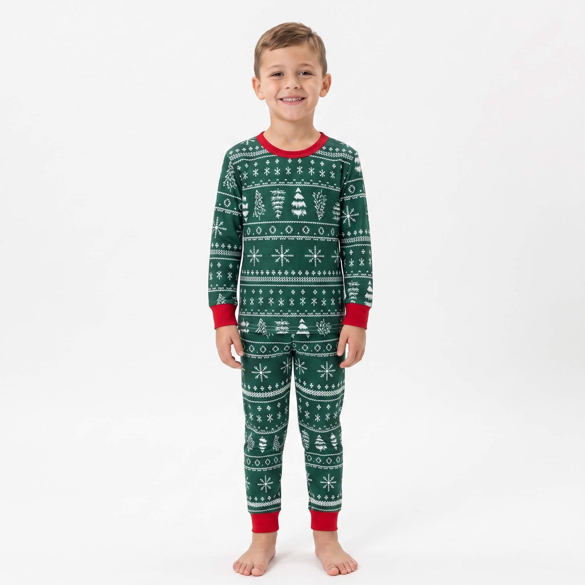 Boy modeling green Christmas pajamas with white Fair Isle tree and snowflake patterns and red cuffs.