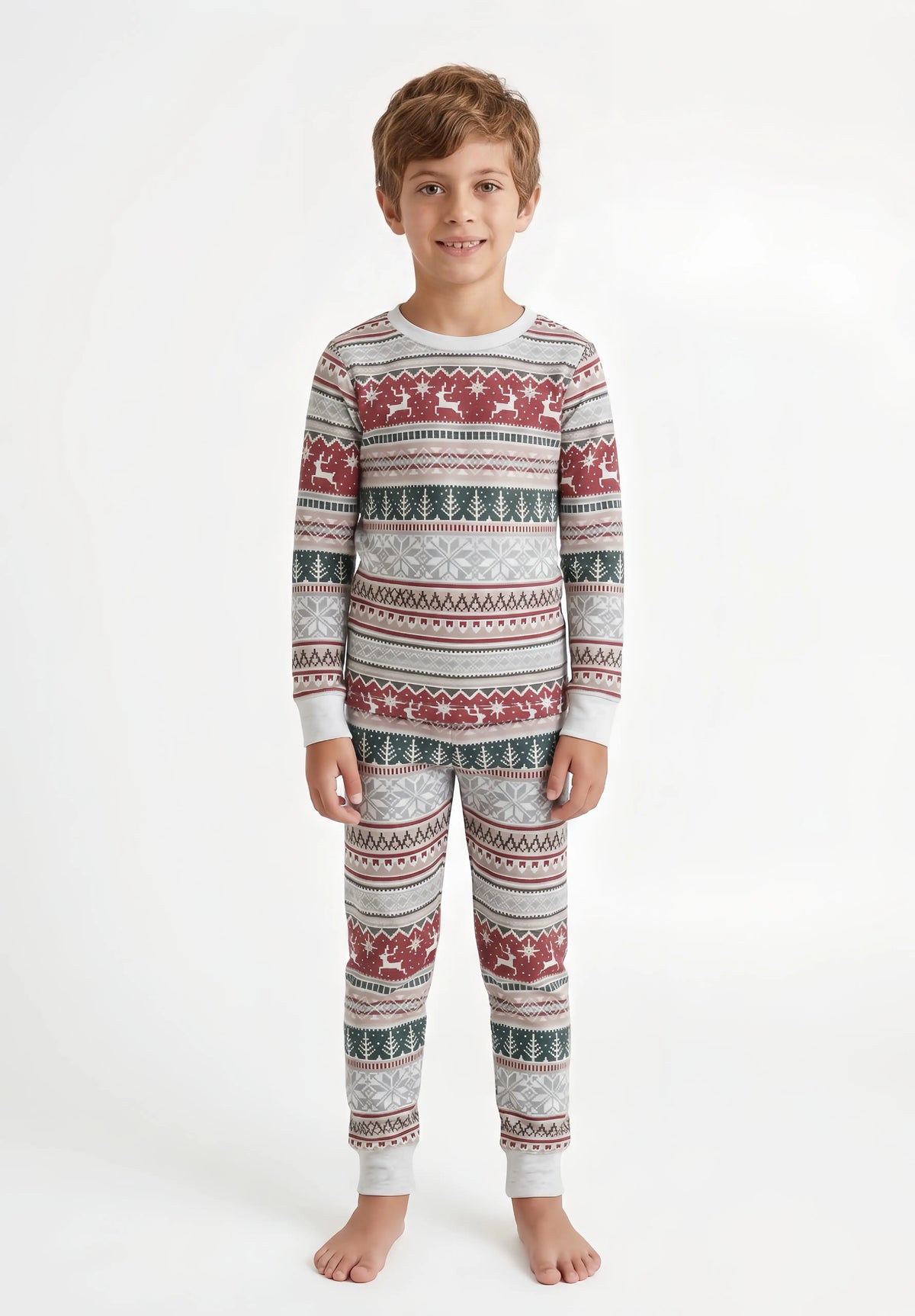 Boy with wavy hair modeling light grey Christmas pajamas with red reindeer bands, green trees and white cuffs.