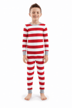 Boy standing in Christmas pajamas with wide red and white stripes, long sleeves and grey cuffs.