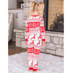Back view of a little girl with pigtails standing in front of a fireplace, displaying the back design of the kids' red and white Fair Isle reindeer holiday sleepwear.