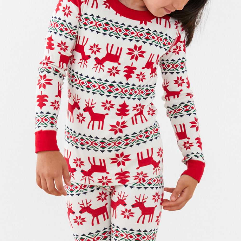 Detailed close-up shot of a kid wearing a long-sleeve red and white Fair Isle reindeer pajama top and matching pants.