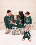 Family wearing green Lights Out reindeer Christmas pajamas with matching printed pants and a baby romper