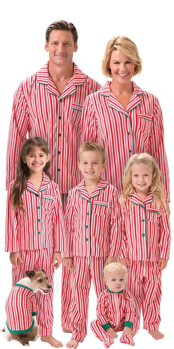 Family of six with a pet dog wearing matching red and white candy cane striped Christmas pajama sets against a white background.