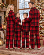 Back view of a family of four in red and black plaid pajamas in a Christmas-decorated cabin.