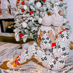 Mother and toddler by a snowy Christmas tree wearing matching white Fair Isle snowflake pajamas with knit beanies.