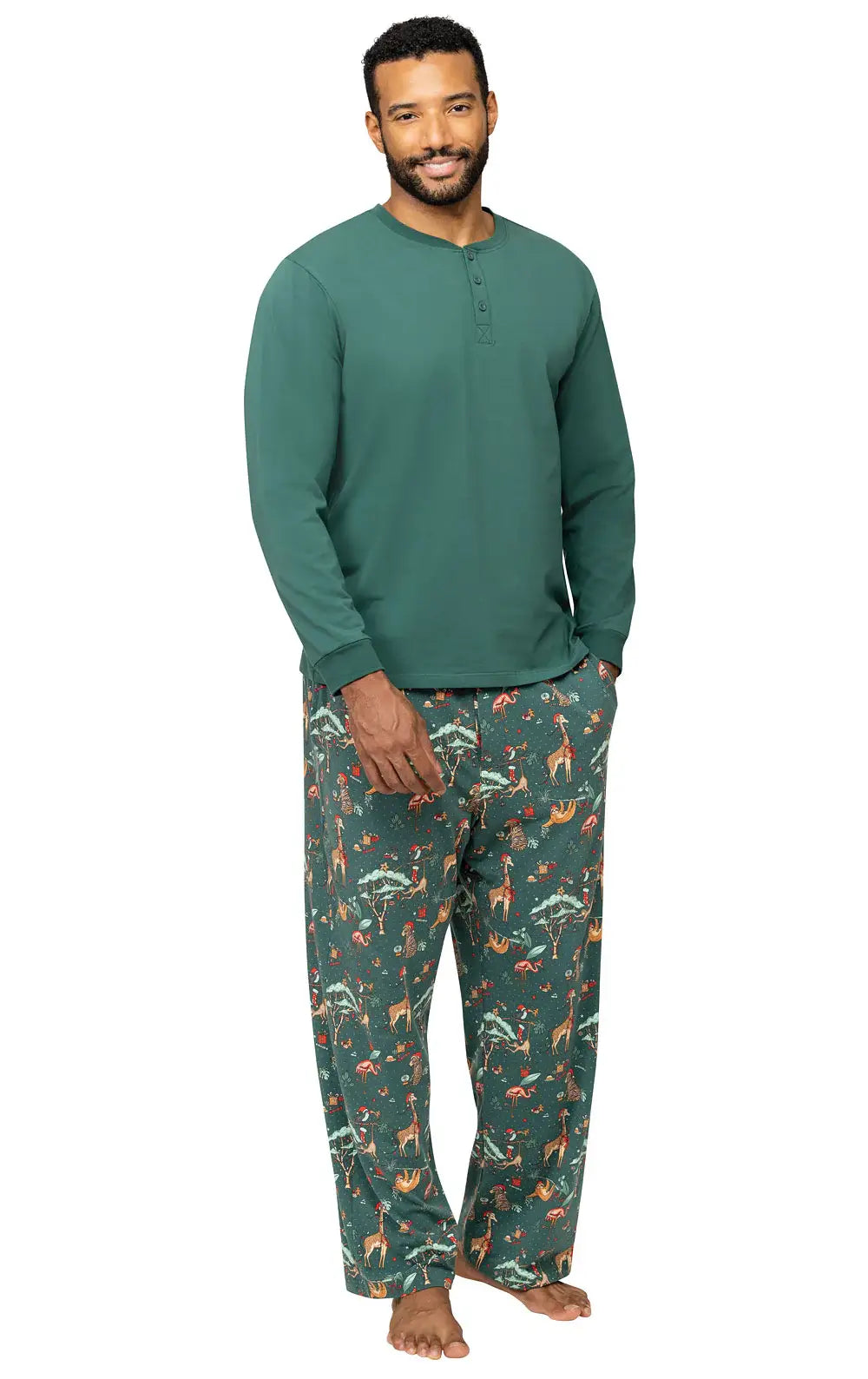 Smiling man standing on a white background modeling a dark green long-sleeve Henley pajama top with matching safari print pants.