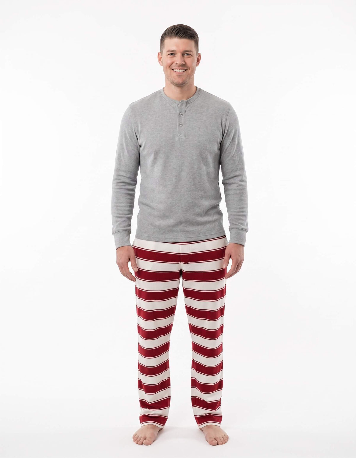 Man modeling a grey long-sleeve Henley with red and white striped Christmas pajama pants.