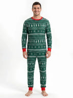 Man wearing green Christmas pajamas with white tree and snowflake rows, a red crewneck and red cuffs.