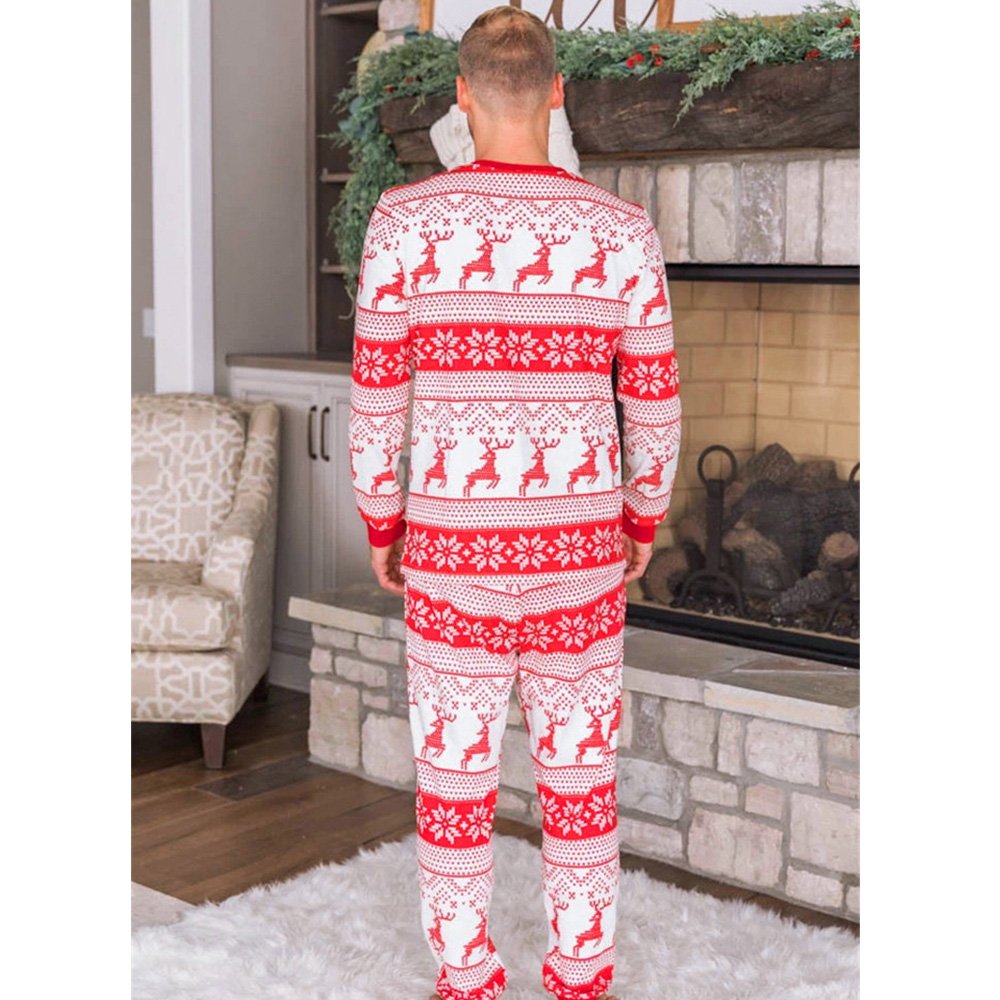 Back view of an adult man standing by a stone fireplace, showcasing the back fit and pattern of the red and white Fair Isle reindeer holiday pajamas.