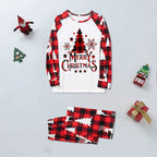 Flat lay display of a long-sleeve white raglan pajama top with red buffalo plaid sleeves alongside neatly folded pants with white pine tree and reindeer silhouettes.