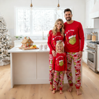 Family wearing red Grinch tops and red-and-white striped Christmas pajama pants in a decorated kitchen