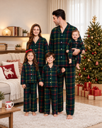 Matching family cotton flannel pajamas in dark green tartan, with adult and kids two-piece sets and a baby romper.