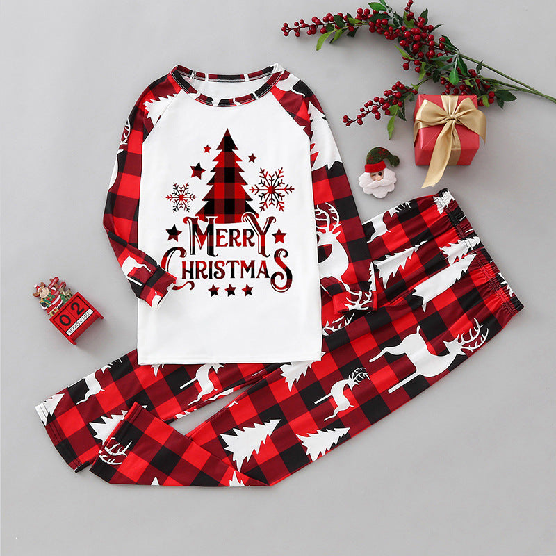 Top-down flat lay view of a two-piece Christmas pajama set featuring red and black buffalo check sleeves, matching deer print pants, and a white raglan top with a Merry Christmas tree design.