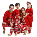 Seated family of four wearing red Christmas tree tops and polar bear pajama pants on white