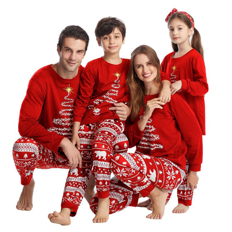 Seated family of four wearing red Christmas tree tops and polar bear pajama pants on white