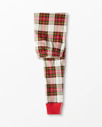Detailed view of folded adult pajama pants featuring a traditional red, green, and cream plaid pattern with bright red ribbed ankle cuffs.