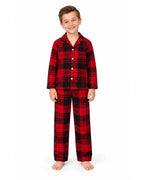 Boy wearing a red and black plaid pajama shirt and long pants on a white background.