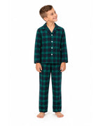 Boy wearing a green and black plaid pajama shirt and long pants on a white background.