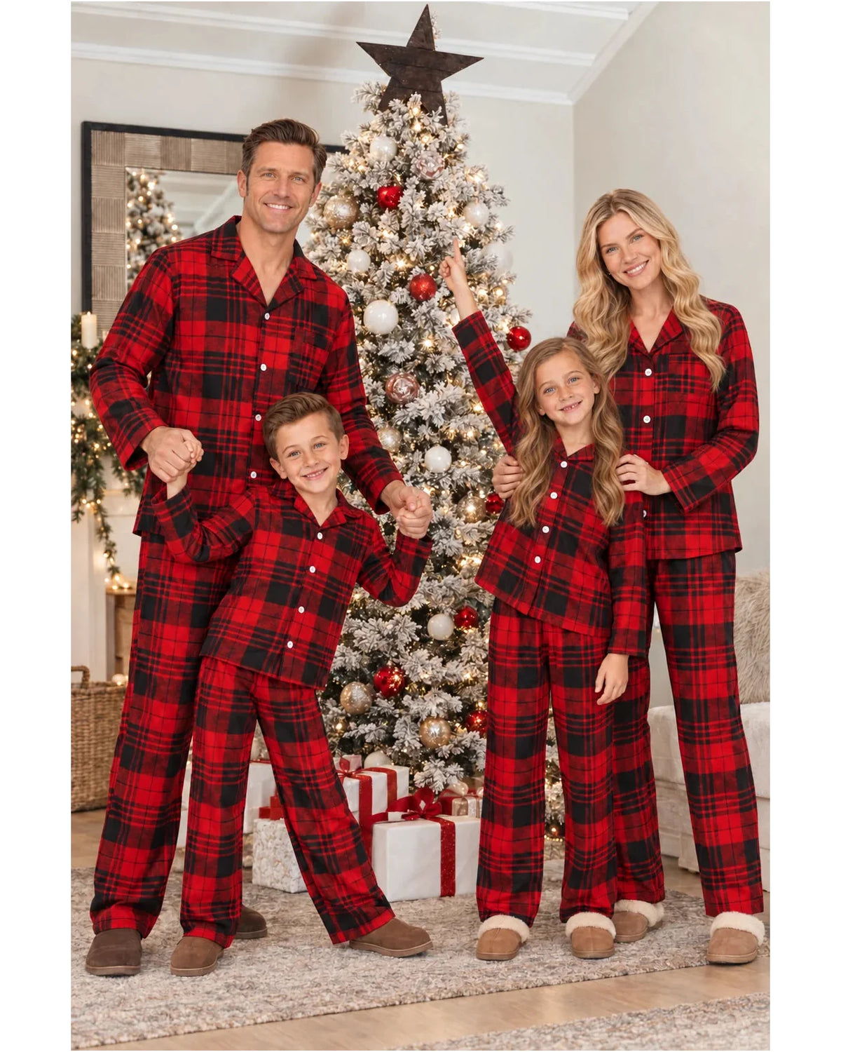 Family of four standing beside a Christmas tree in matching red and black plaid pajamas.