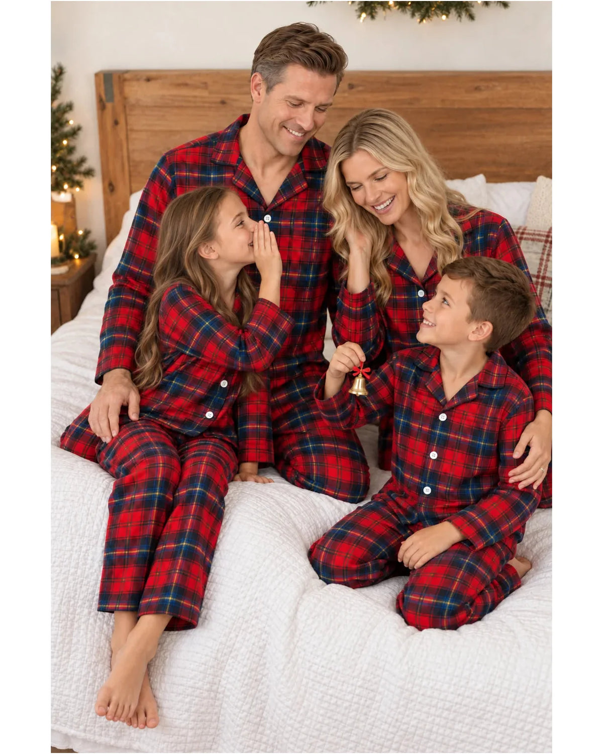 Family seated on a bed wearing matching red and blue plaid pajamas.