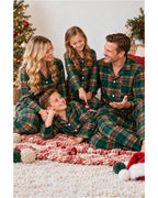 Family seated on a bed wearing matching light green tartan pajama shirts and pants.