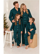 Adults and children in matching green and black plaid pajamas posing beside a wooden stool.