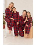 Adults and children wearing red and blue plaid pajama shirts and pants in a bright room.