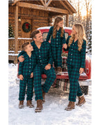 Family in matching green and black plaid pajamas posing by a red truck outside a wooden cabin.