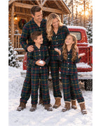 Family wearing dark green tartan pajamas beside a red truck in a snowy cabin setting.