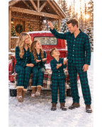 Family wearing green and black plaid pajamas beside a red truck in a snowy cabin setting.