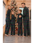 Rear view of a family in dark green tartan pajama shirts and pants beside a Christmas tree.