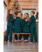 Rear view of a family wearing green and black plaid pajama shirts and pants in a Christmas cabin.