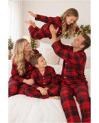 Family wearing red and black plaid pajamas on a bed as the father lifts his daughter.