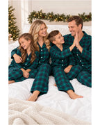 Family in green and black plaid pajamas sitting on a bed as the father and son high-five.