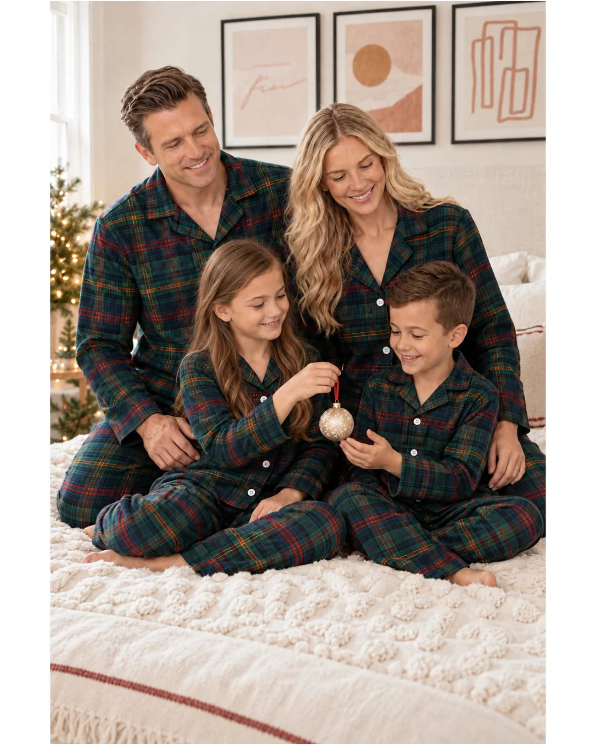 Family seated together on a textured bedspread wearing matching dark green tartan pajamas.