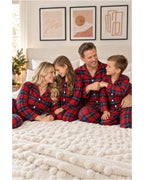 Family wearing red and blue plaid pajamas seated on a textured bedspread.