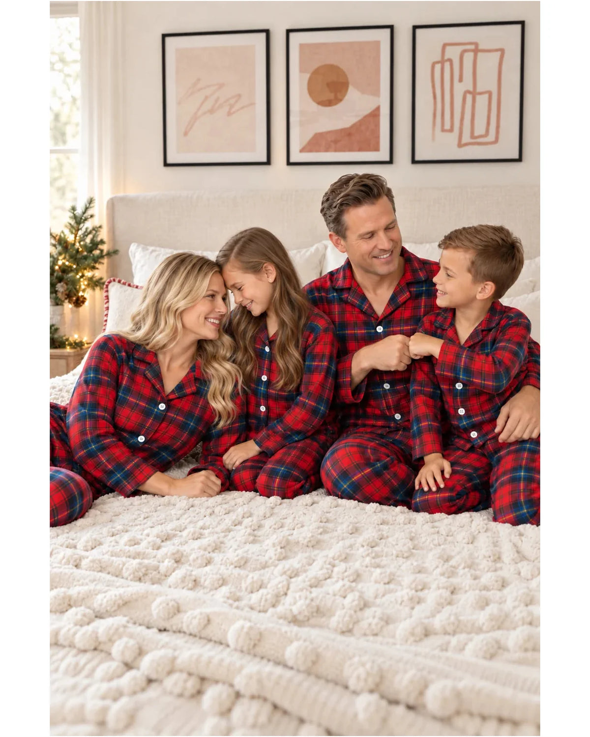 Family wearing red and blue plaid pajamas seated on a textured bedspread.