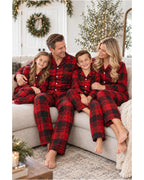 Family seated on a sofa in matching red and black plaid pajamas.
