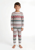 Boy with short dark hair wearing light grey Christmas pajamas with red reindeer, green trees and white cuffs.