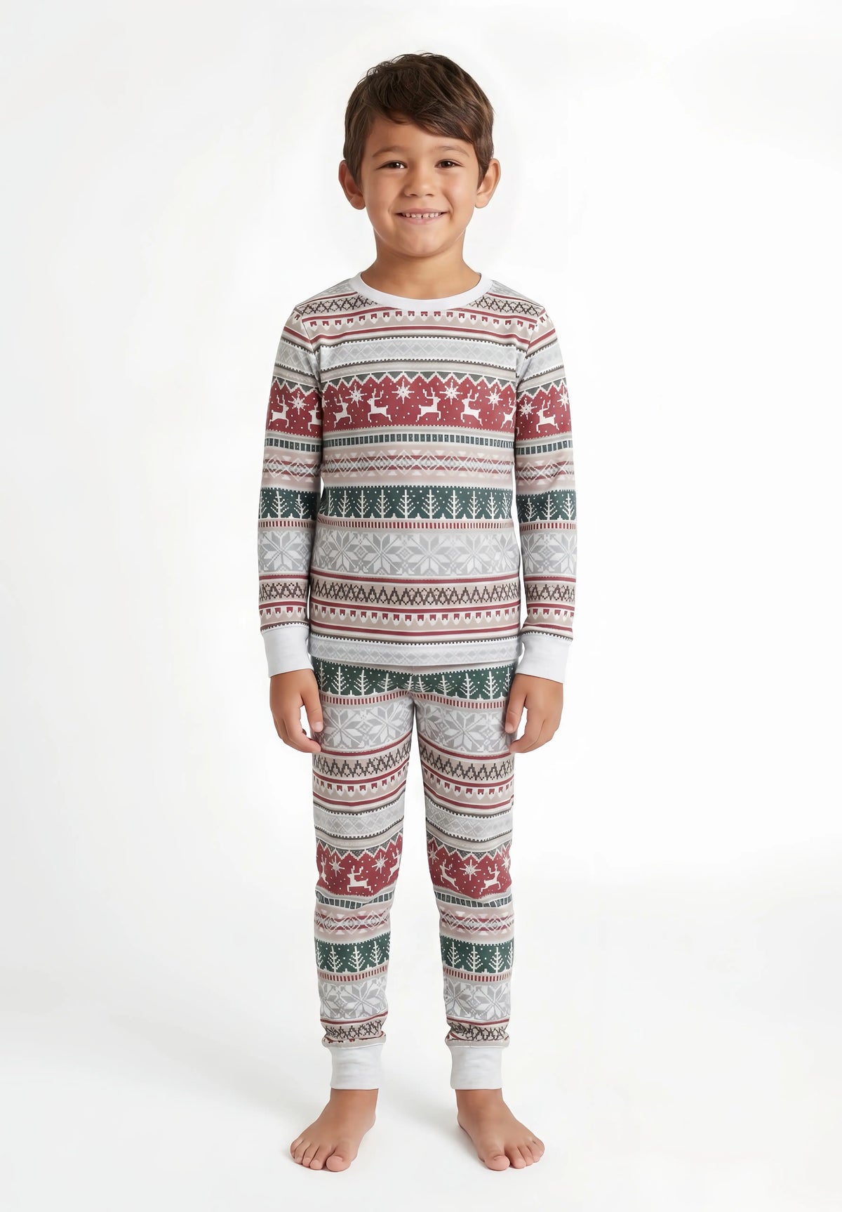 Boy with short dark hair wearing light grey Christmas pajamas with red reindeer, green trees and white cuffs.