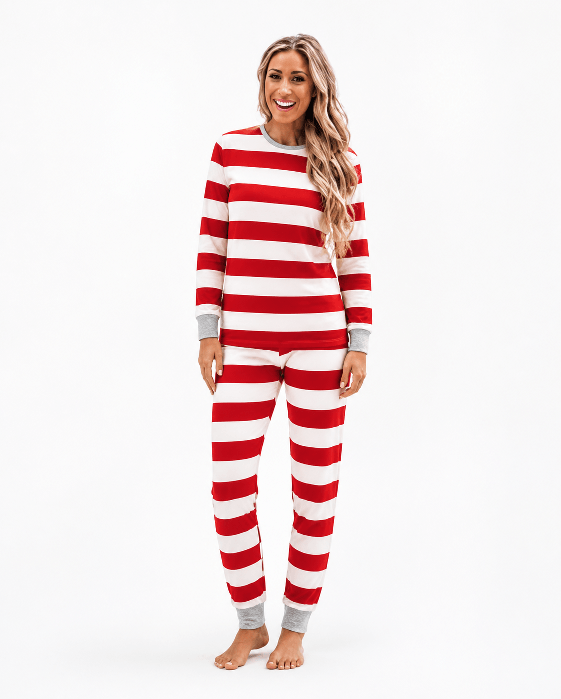 Woman modeling Christmas pajamas with wide red and white stripes, long sleeves and grey cuffs.