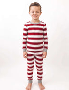 Boy modeling red and white striped Christmas pajamas with grey cuffs against a white background.
